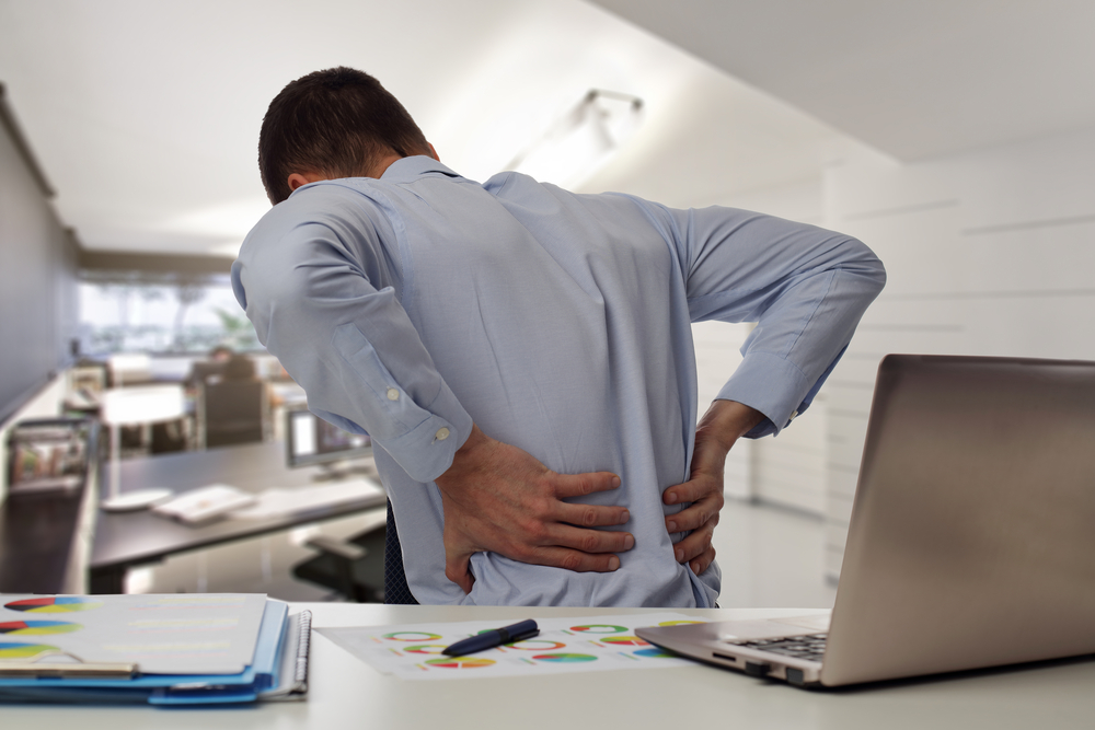 Man holding lower back in pain with sacroiliac joint dysfunction